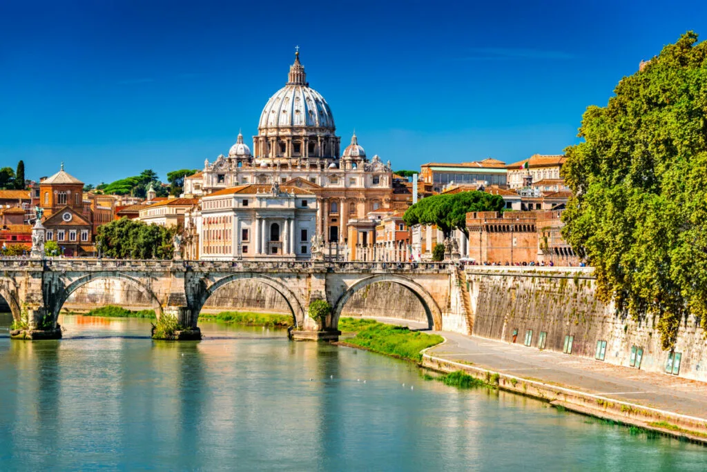 Rome, Italy. Vatican dome of Saint Peter Basilica (Italian: San Pietro) and Sant Angelo Bridge, over Tiber river.