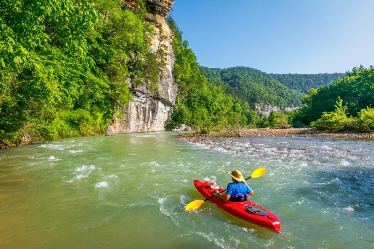 A kayaker is floating down the River