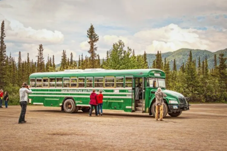 Green transit bus in Denali National Park with tourists