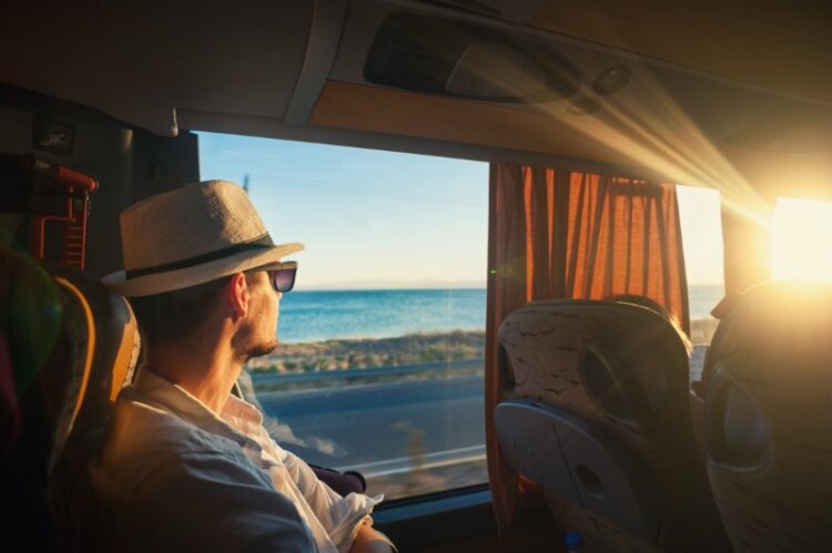 Man wearing hat looking outside window, travelling in bus