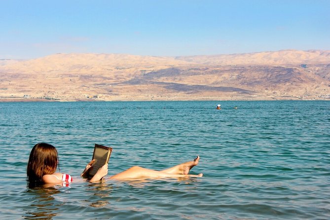woman reading while sunbathing in the dead sea