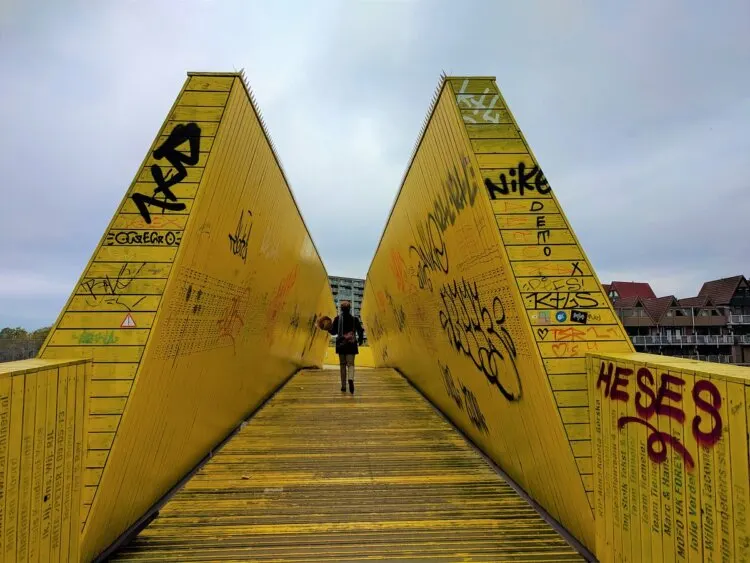 man walking at the yellow wooden pedestrian bridge at the Luchtsingel