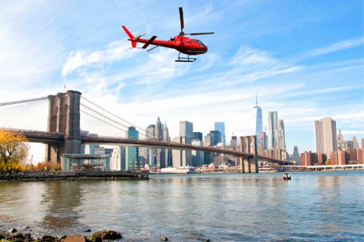 Helicopter flying over New York City skyscrapers and Brooklyn Bridge