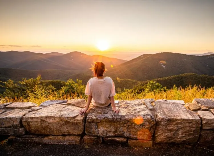 View of woman sees sunset over blue ridge mountains 