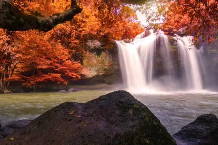 Beautiful waterfall with sunlight and orange leaves in Tham Kong Lo Cave