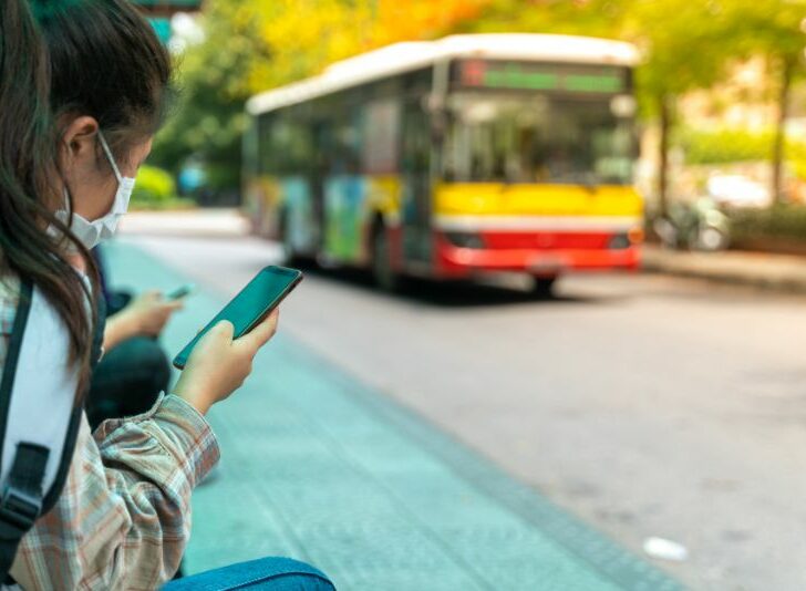 Asian young girl use smartphone waiting for bus