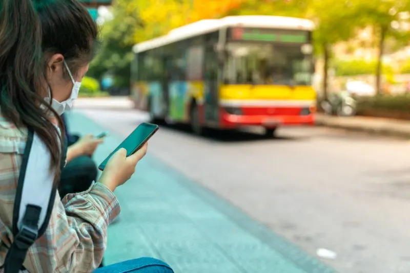 Asian young girl use smartphone waiting for bus