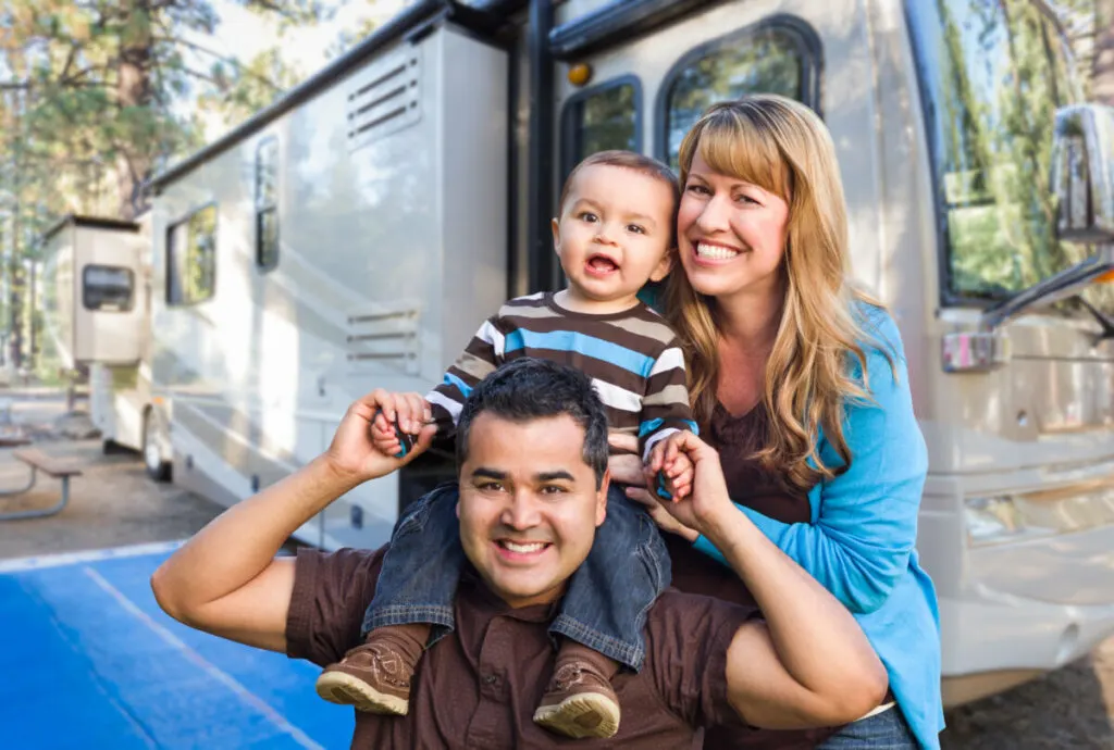Happy Young Mixed Race Family In Front of Their Beautiful RV At The Campground