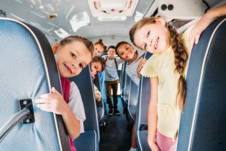 Group of cute schoolchildren riding on school bus