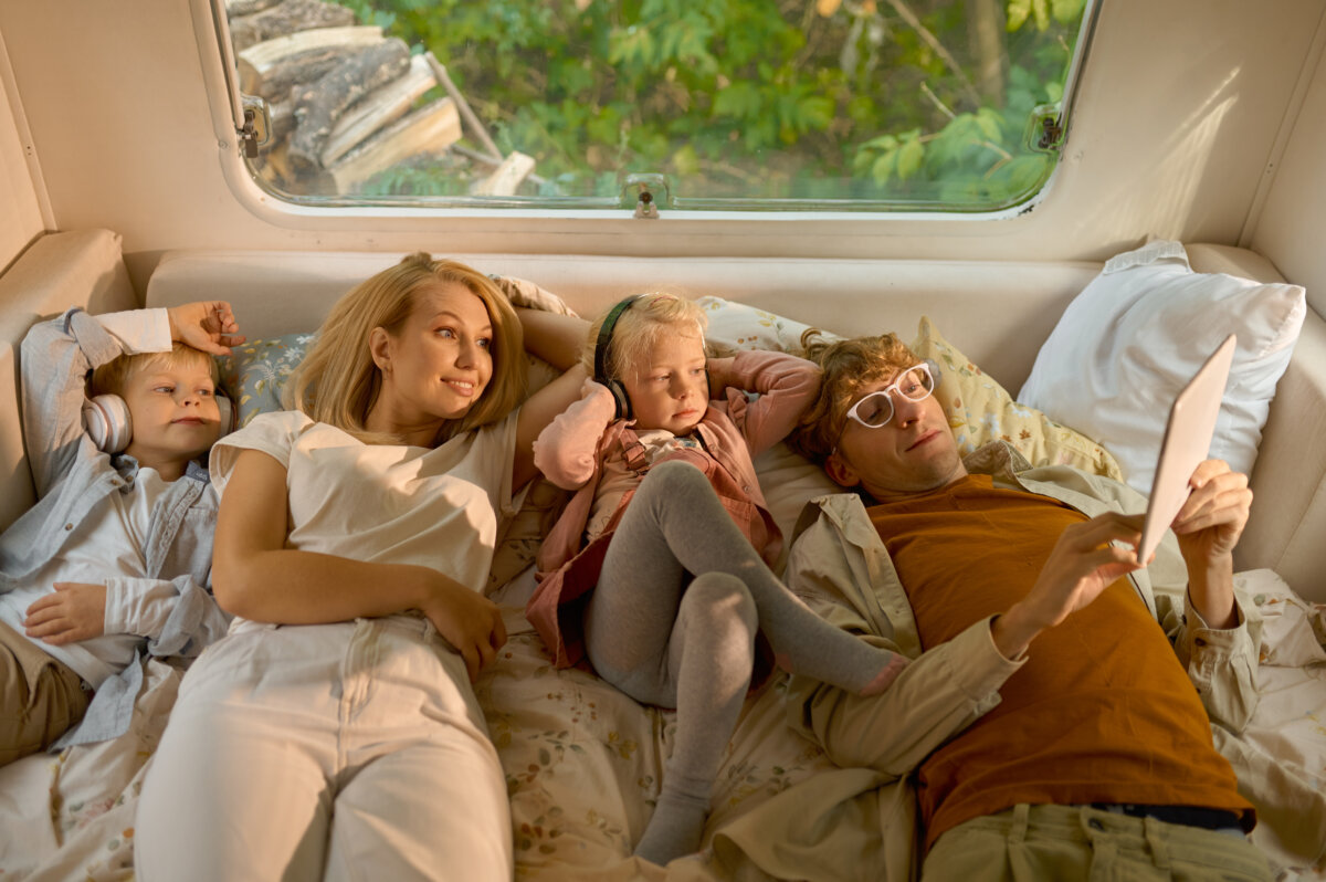 Cheerful family lying in bed in motorhome, camping
