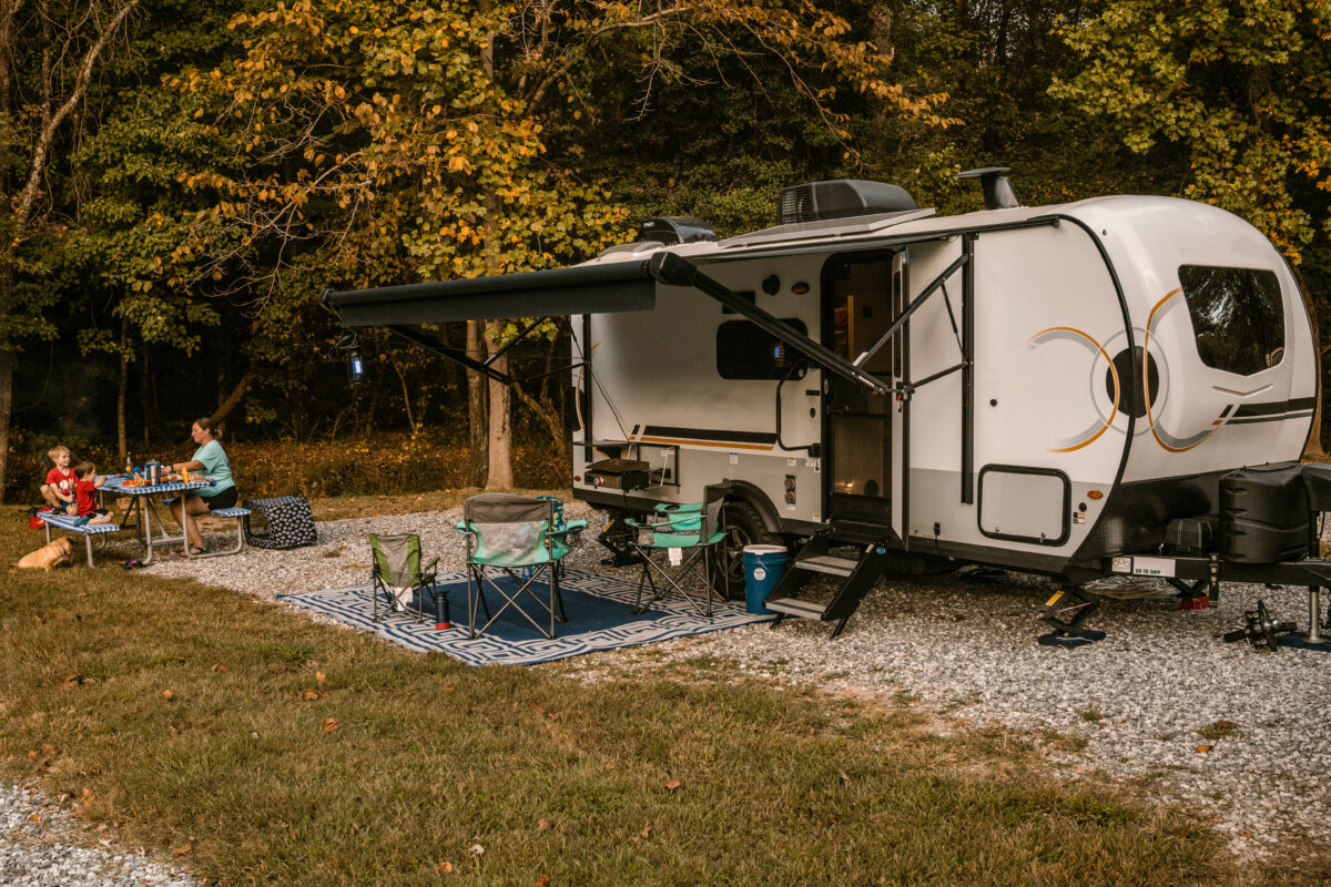 Family camping with travel trailer camper and eating at picnic table