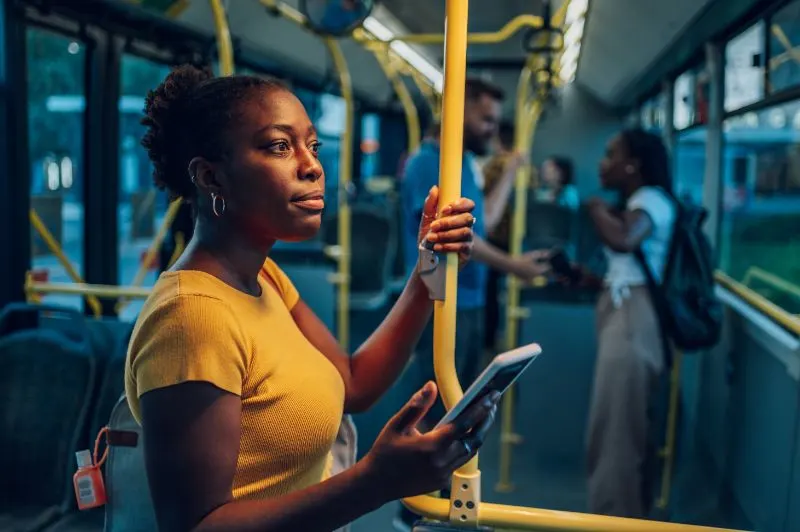 African american woman riding in a bus and using a smartphone 