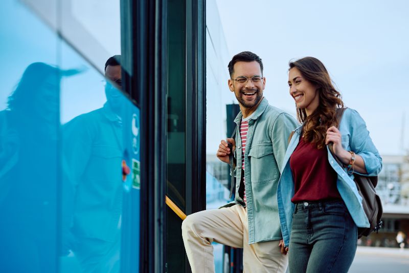 Cheerful couple boarding in public transport at bus station