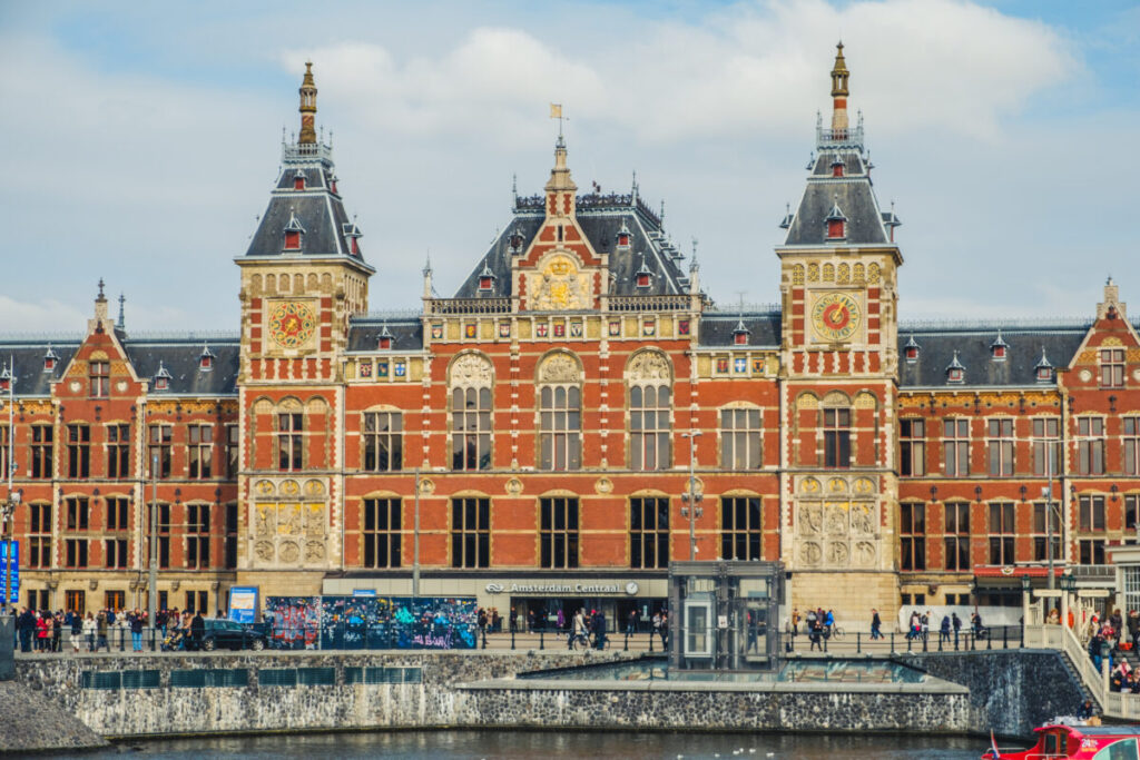 Amsterdam Centraal Station exterior showcases stunning neo-Renaissance architecture near scenic waterways.