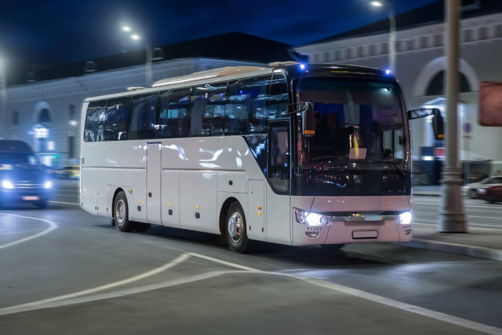 White bus traveling at night on a busy road