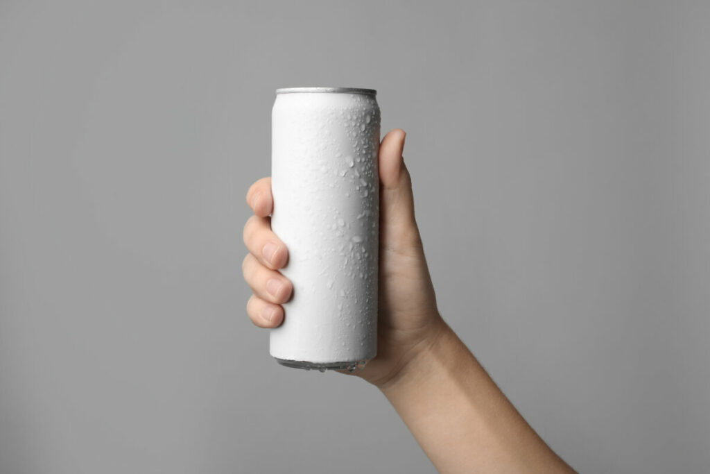Close-up of a hand holding a canned beer on grey background