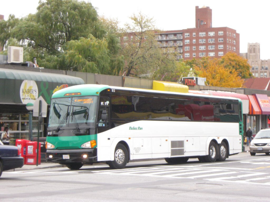 Modern bus on busy city street near Kabirs Bakery, heading to St. Johns University.