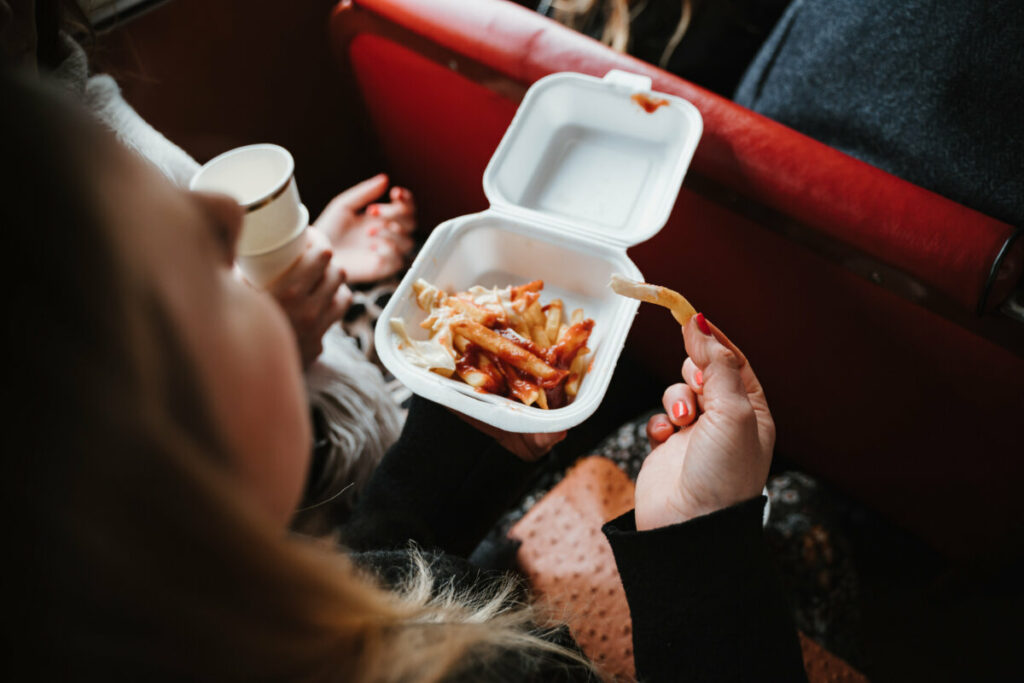 Close-up of a woman eating fries with ketchup
