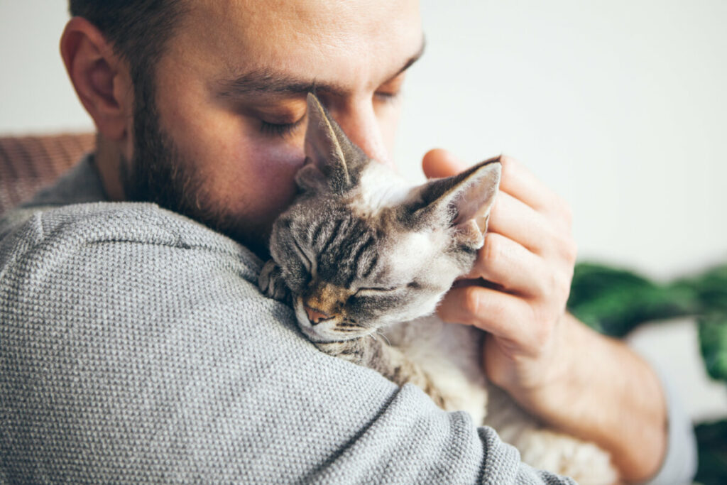 Close-up of a man holding and hugging a small cat