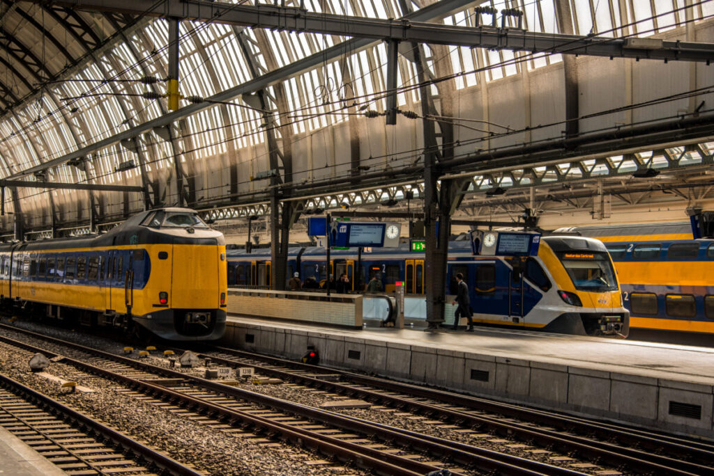 Bustling Amsterdam train station with modern Dutch trains and busy commuters in March 2022.