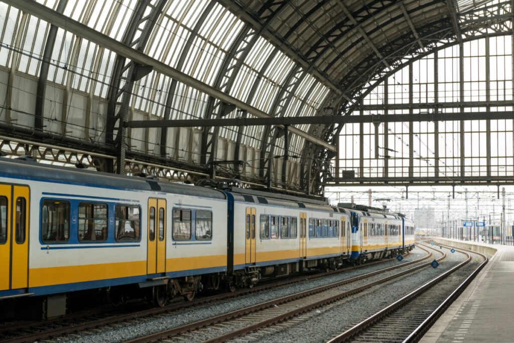 Modern train at Amsterdam Centraal station showcasing vibrant architecture and bustling urban transit.