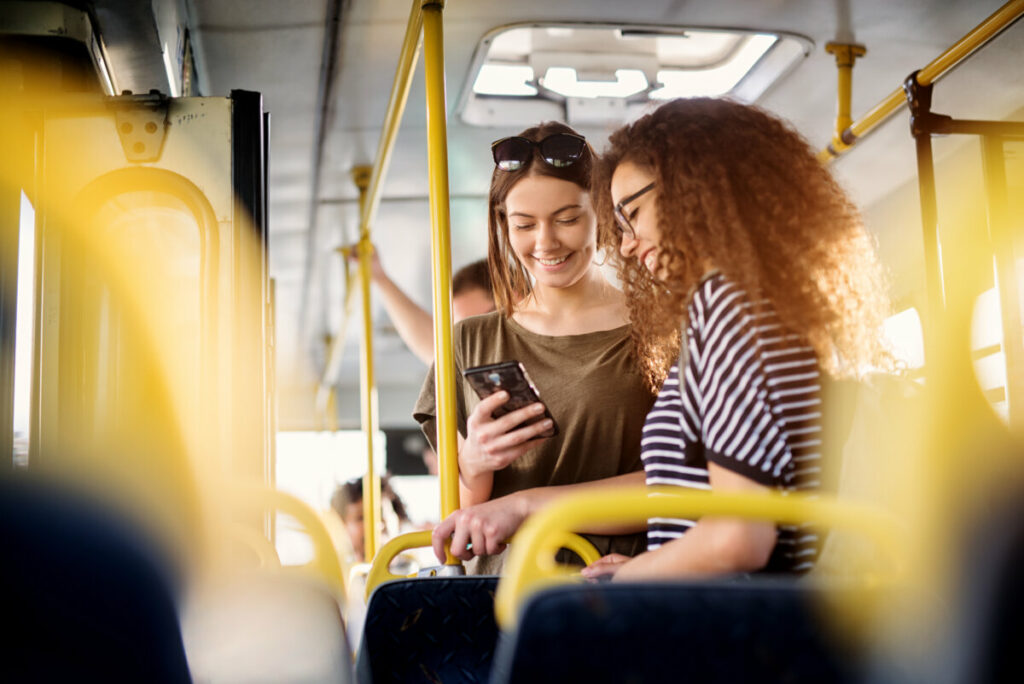 Two young female standing inside a bus